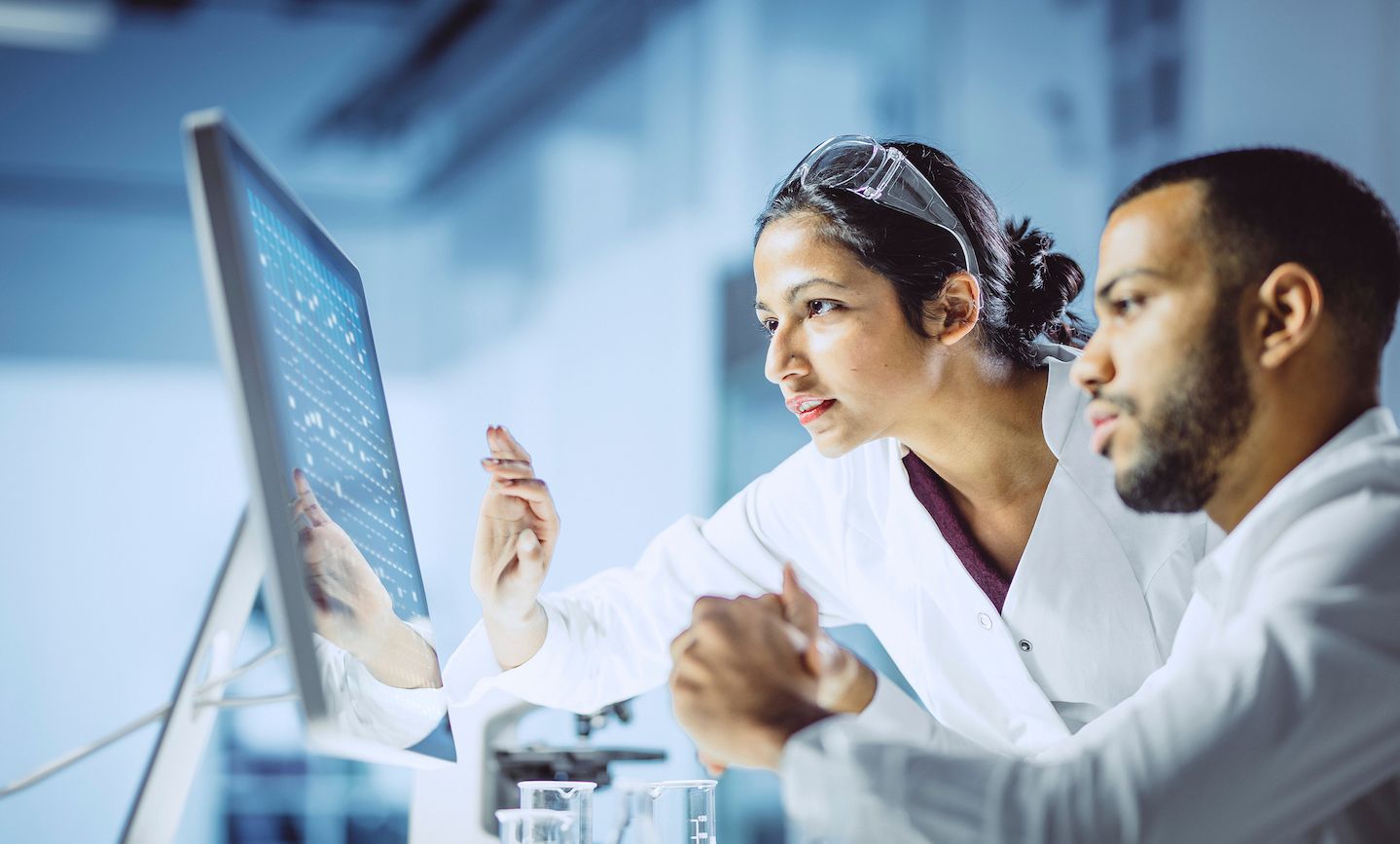 A male and female researcher are examining information on a computer screen